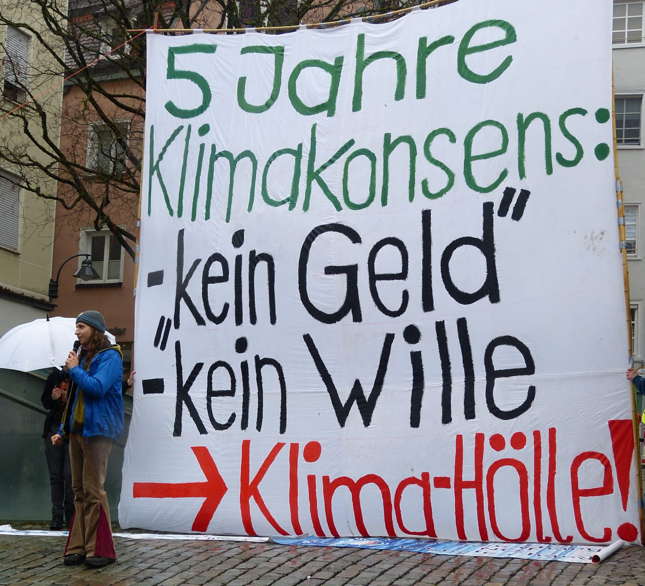 Großbanner an Bambusstangen mit der aufschrift: 5 Jahre Klimakonsens - kein geld, - kein wille -> Klimahölle